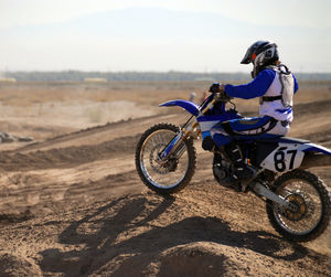 Man riding bicycle on desert against sky
