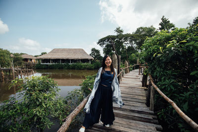 Portrait of smiling woman standing on footbridge in village