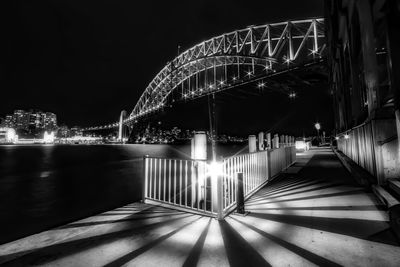 Illuminated bridge over river in city at night