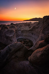 Scenic view of sea against dramatic sky during sunset