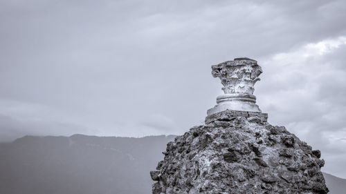 Low angle view of statue on rock against sky