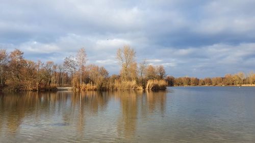 Scenic view of lake by trees against sky