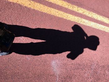 Low section of man shadow on road
