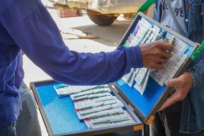 Midsection of man buying lottery tickets from vendor