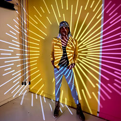 Man with umbrella standing against illuminated wall