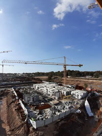 Cranes by buildings against sky in city