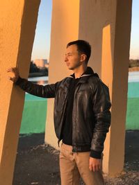 Thoughtful young man standing against columns during sunset