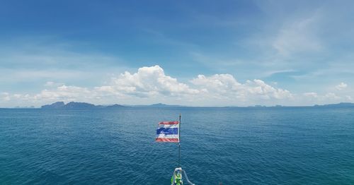 Thai flag with sea in background against blue sky