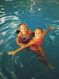 High angle portrait of sisters playing in swimming pool