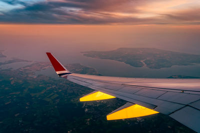 Airplane flying over sea against sky during sunset