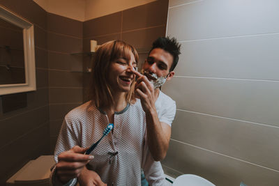 Man applying shaving cream on girlfriend nose