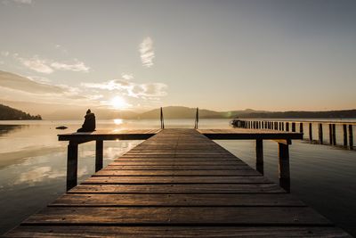 Pier over lake against sky during sunset