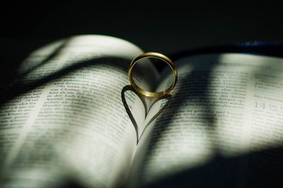 Close-up of ring with heart shape shadow on book