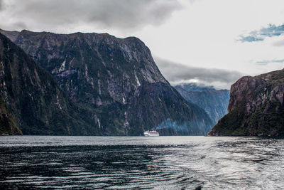 Scenic view of sea by mountains against sky