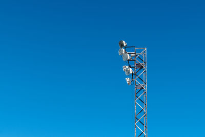 Low angle view of communications tower against clear blue sky