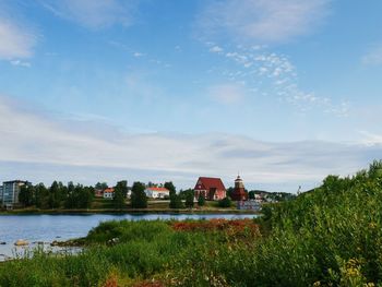 Houses on field by building against sky