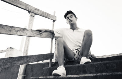 Low angle view of man looking away while sitting on staircase