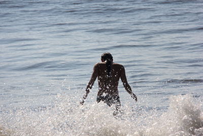 Rear view of young woman enjoying in sea