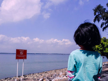 Rear view of girl looking at sea against sky