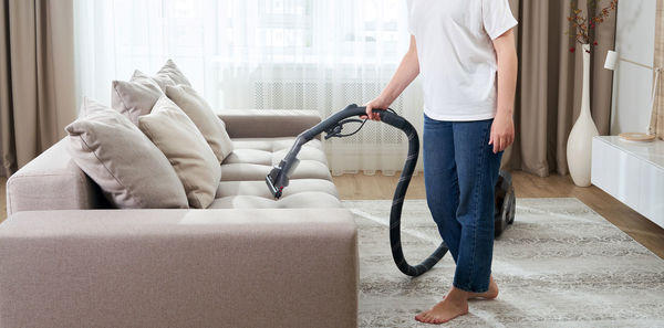 Midsection of woman holding sofa at home