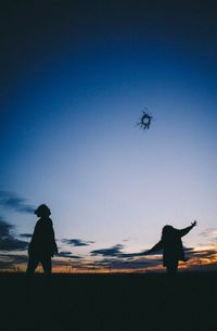 Silhouette people on field against clear sky