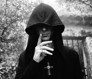 Young man wearing hood holding rosary beads