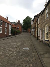 Street amidst houses in town against sky