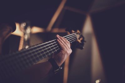 Cropped hand of man playing guitar in darkroom