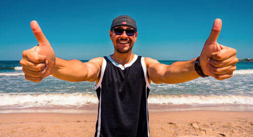 Portrait of man wearing sunglasses at beach against sky