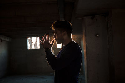 Side view of young man drinking against wall