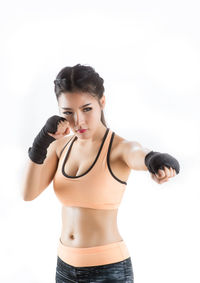 Portrait of young woman standing against white background