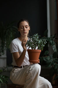 Young woman gardener taking care of green home plant in pot. home gardening, love of houseplants.