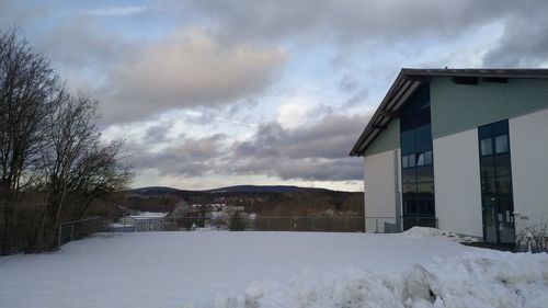 Snow covered landscape and houses against sky