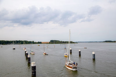 Sailboats moored on sea against sky