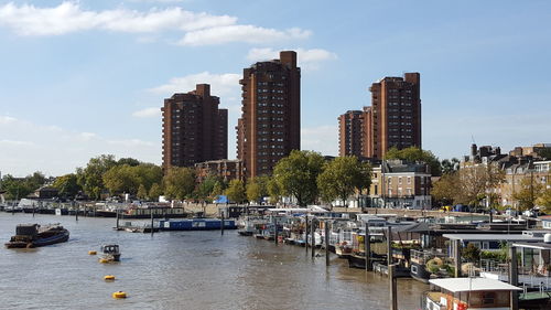 Boats in river by buildings against sky in city battersea