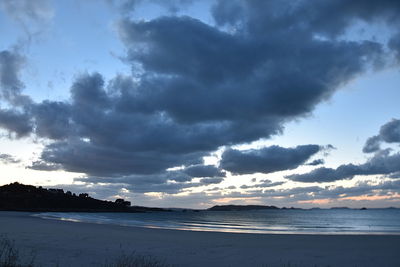 Scenic view of beach against cloudy sky