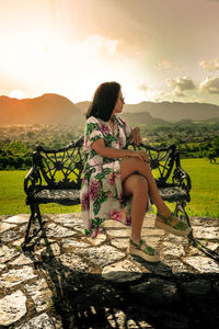 Woman looking at camera against sky during sunset