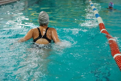 A girl swimming in a swimming pool. view from the back.