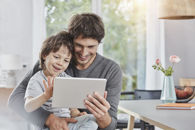 Happy father and son using tablet at home together