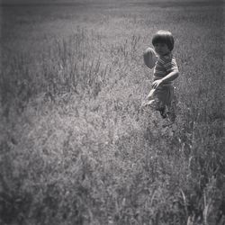 Portrait of boy playing with ball amidst field