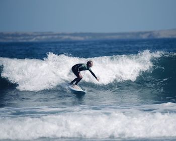 Man surfing in sea against sky