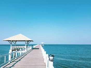 Pier over sea against clear blue sky