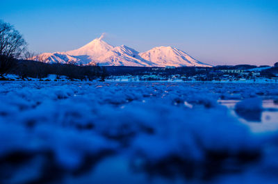 Surface level of snow covered land against clear blue sky