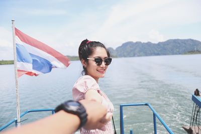 Cropped image of boyfriend holding girlfriend hand on boat in lake