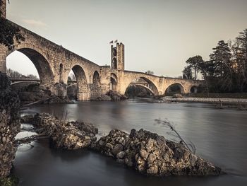 Arch bridge over river against clear sky