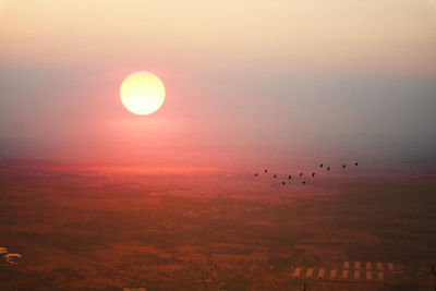 Sunset on evening sky over mountain and silhouette bird flying over dairy farm in lopburi thailand