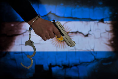 Close-up of a hand holding metal against blue wall