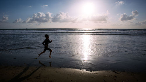 Side view of boy on beach against sky