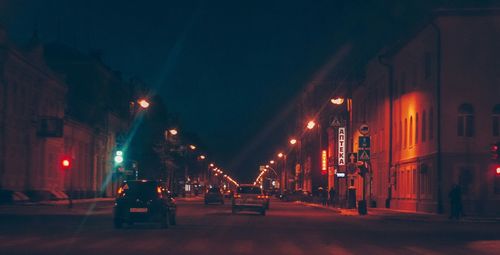 Illuminated street amidst buildings in city at night