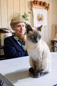 Cat sitting on table with man in background